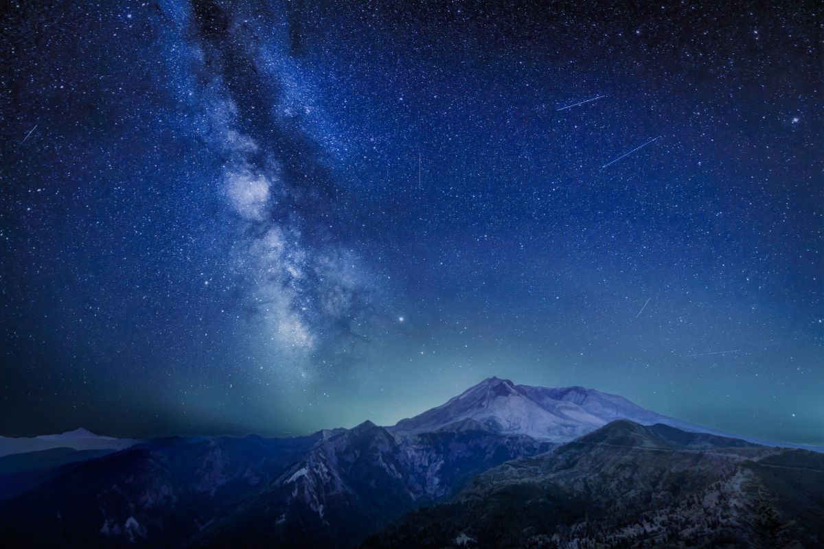 米ワシントン州にあるセントヘレンズ山上空を流れる「みずがめ座δ南流星群」の流れ星と天の川。左手奥にオレゴン州の最高峰フッド山が見え、同州最大の都市ポートランドの街明かりがセントへレンズ山の後背を照らしている（Diana Robinson Photography/Getty Images）