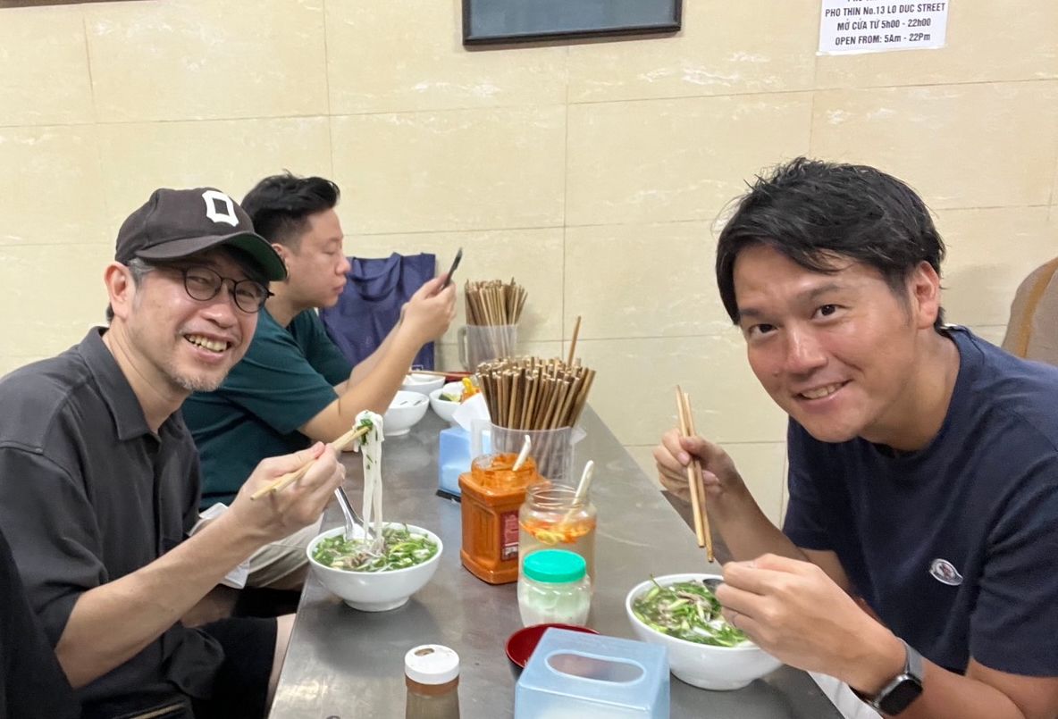 社用車は、とあるフォー屋さんに到着。ぜひここのを食べて欲しいと。こうやって同じものを食べながら、本社経営陣やベトナムの方と熱く話しているのだろう。右が緒方氏。左が筆者（筆者提供）