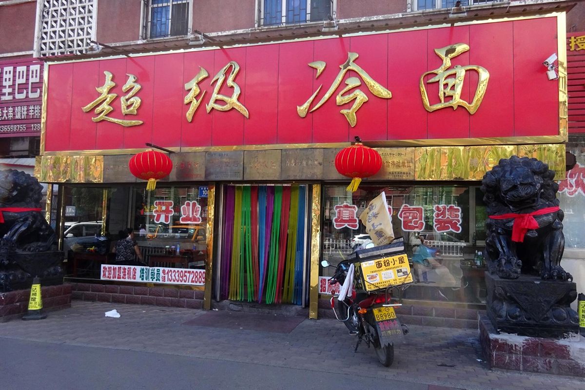 ド派手でインパクトのある赤字のプレートに金色の店名を記した鶏西で人気の「超級冷面」。オープンは1990年代だ