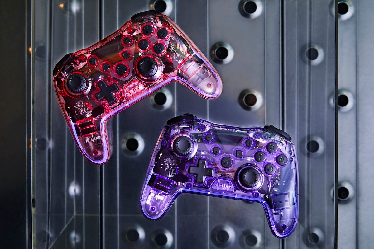 LEDランプで光るスケルトン素材のクリアゲームコントローラーは、税込3,300円。写真はピンク（上）とパープル（下）。パステルカラーが人気のワイヤレスゲームコントローラー（税込2750円）と累計35万個の大ヒット。