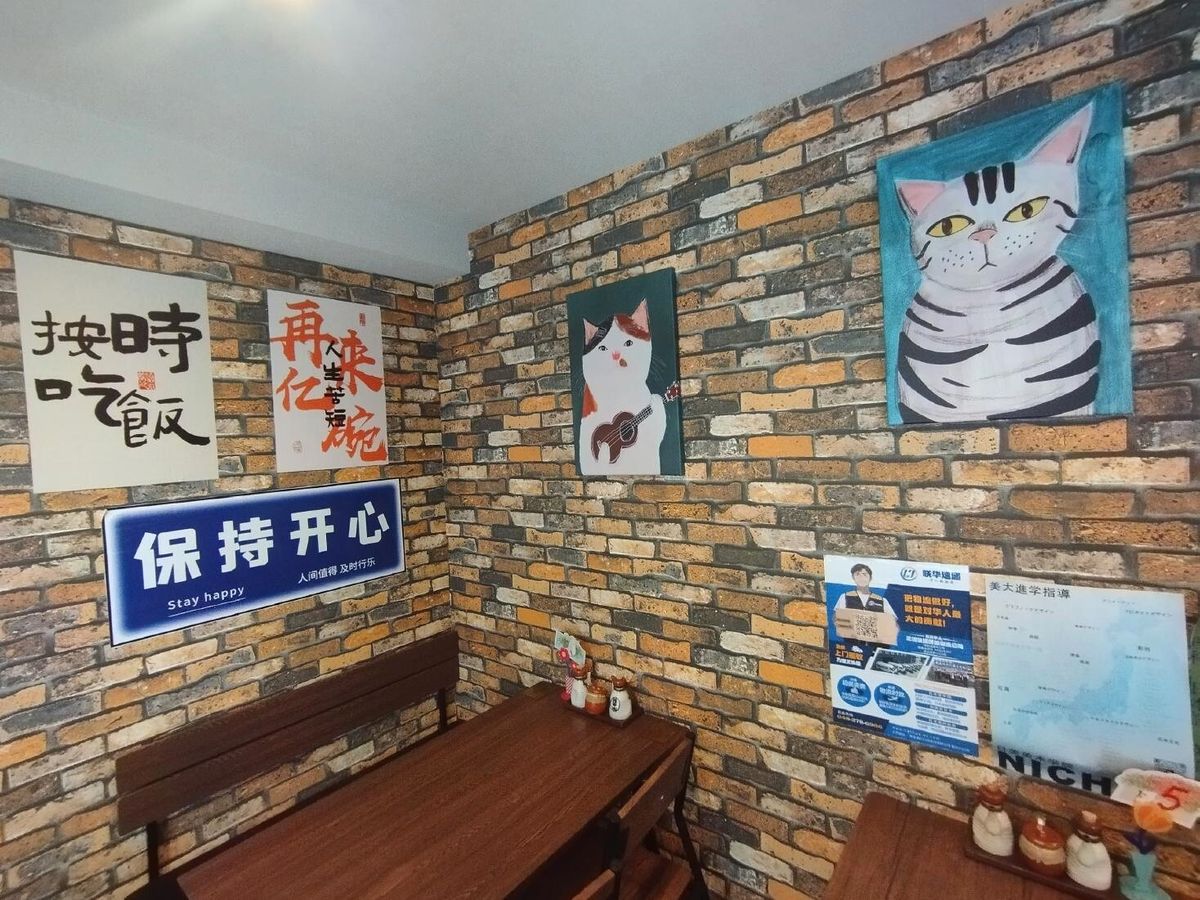 ネコのイラストや中国語のジョークが書かれた貼紙のある「小食堂」の内装は、中国ではふつうに見かけるものだ
