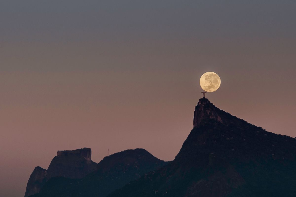 ブラジル・リオデジャネイロのコルコバードの丘に立つキリスト像と、その背後に昇るストロベリームーンの満月。2023年6月4日撮影（Donatas Dabravolskas / Shutterstock.com）