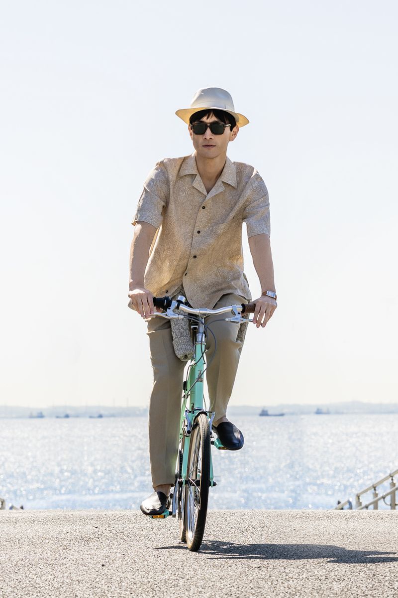 シャツ261800円、パンツ225500円、腰に巻いたカーディガン448800円、靴151800円、ハット653400円、サングラス159500円〈すべてロロ・ピアー ナ／ロロ・ピアーナ ジャパンTel:03-5579-5182〉時計1399200円〈ジャガー・ルクルトTel:0120-79-1833〉自転車はスタイリスト私物