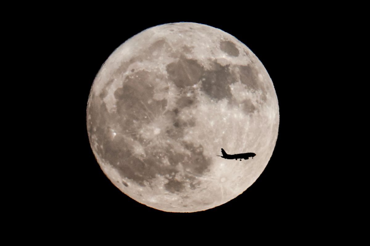 米ロサンゼルス上空に昇る7月の満月「バックムーン」と、その手前を通過する航空機の機影。2023年7月2日撮影（Ringo Chiu / Shutterstock.com）
