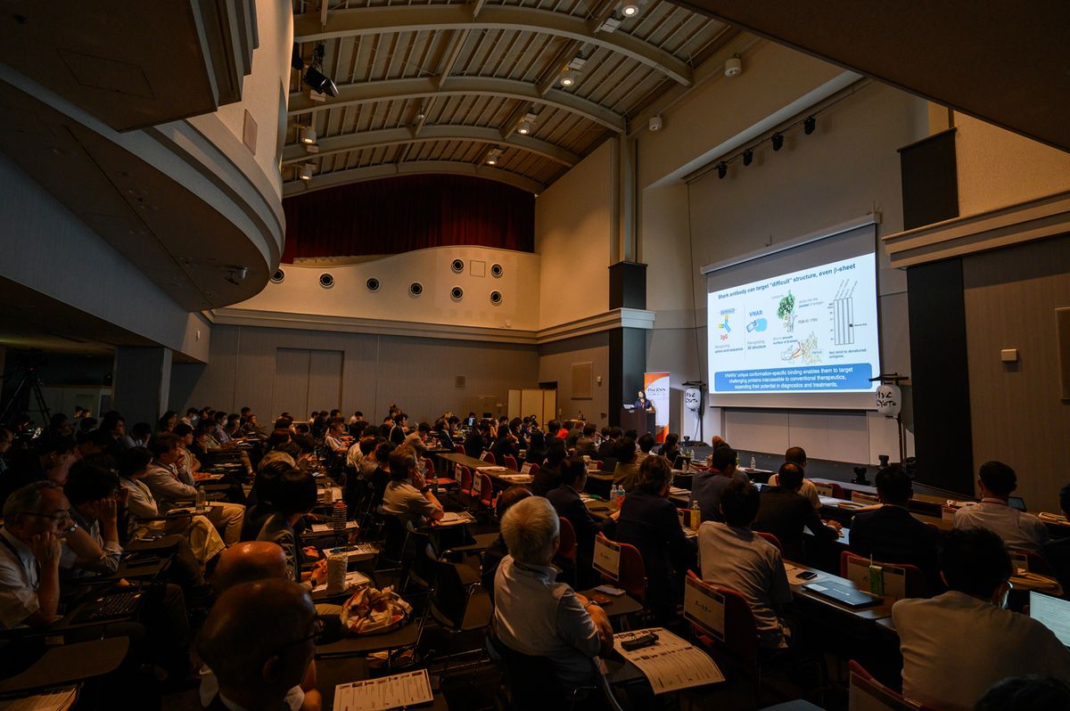 （上）登壇者の1人で、Physiologas TechnologiesのCEO 宮脇一嘉。水道水を使わず在宅透析治療を可能とする「給水不要の血液透析システム」を開発しており、今回9つの賞のうち2つを受賞した。（下）会場はほぼ満席で、立ち見がでるほどの賑わい振りだった。壇上で発表しているのはSharkey Technologies CEOのジョウ・ウェイ