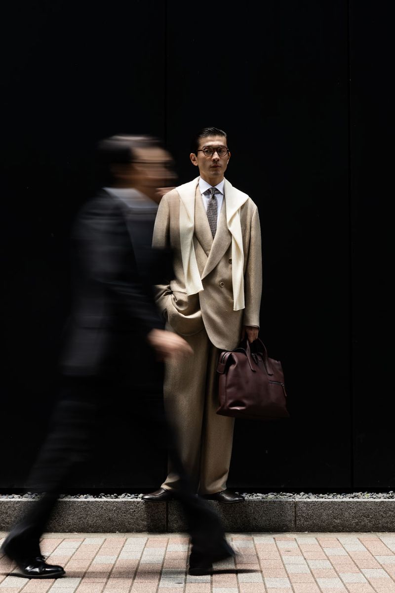 ジャケット627000円、パンツ440000円、 シャツ137500円、タイ 参考商品、肩にかけたセーター352000円、靴190300円、バッグ462000円〈すべてジョルジオ アルマーニ／ジョルジオ アルマーニ ジャパン Tel:03-6274-7070〉メガネ52140円〈ジョルジオ アルマーニ／ルックスオティカジャパン カスタマーサービス Tel:0120-990-307〉