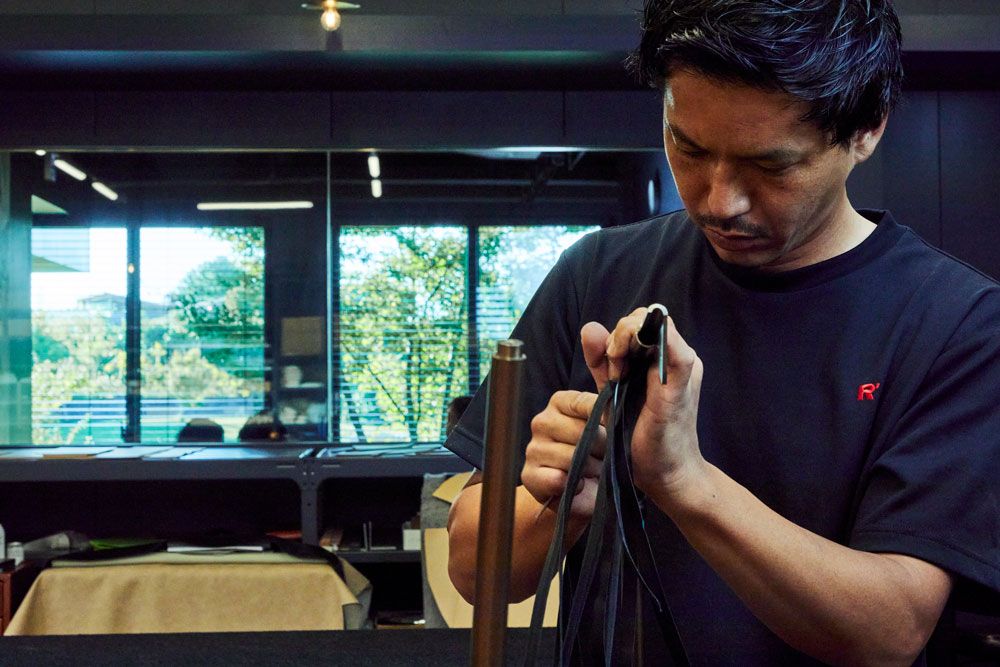 チェアのフレームに厚革を編み込む工程。細部にわたり職人たちの技が光る