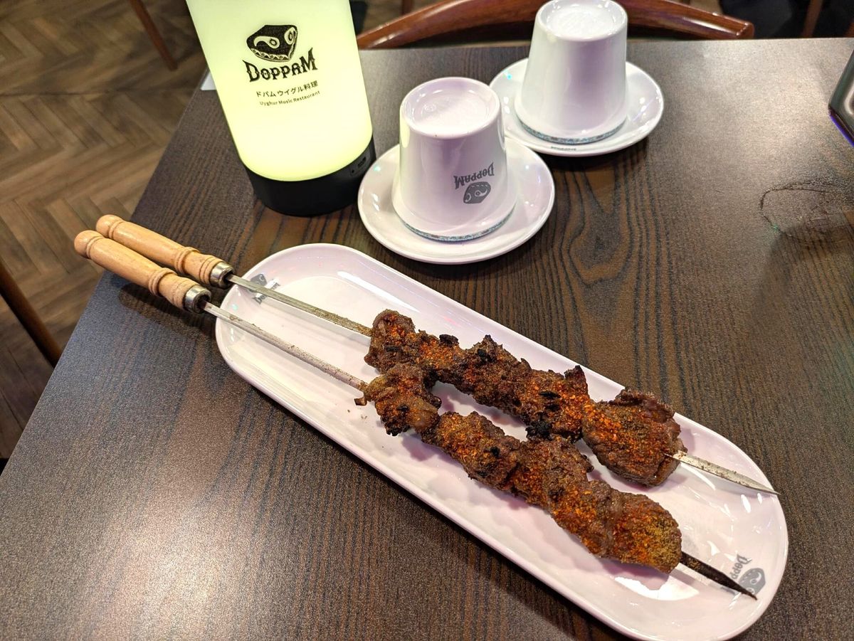 この店の羊肉のシシカバブは、剣のような長い串に刺された中央アジア風の味つけだ