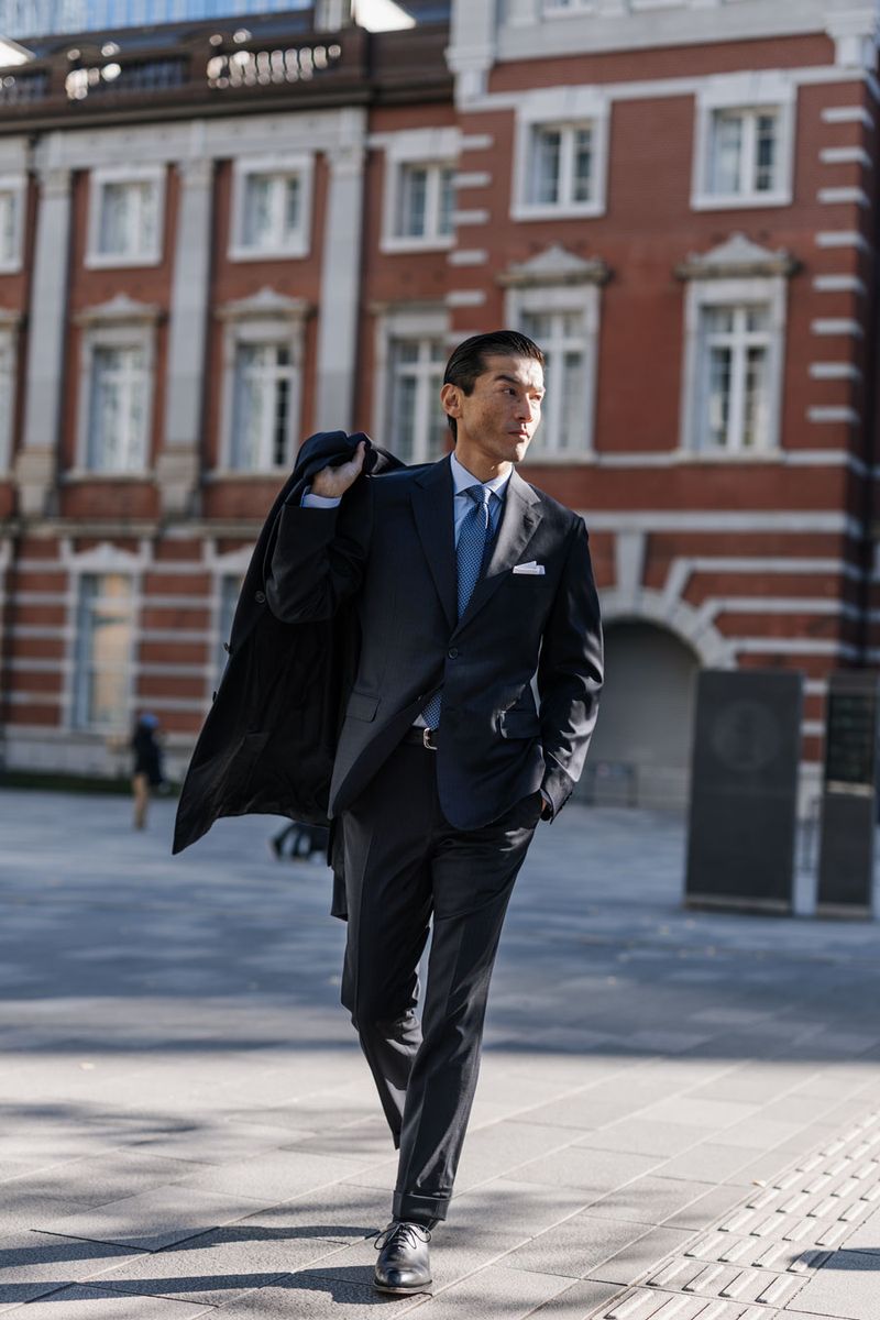 スーツ1050000円〜［オーダー参考価格］、シャツ154000円、タイ、ベルトともに参考商品、チーフ27500円、靴218900円、手に持ったコート1155000円〈すべてブリオーニ／ブリオーニ クライアントサービスTel:0120-200-185〉