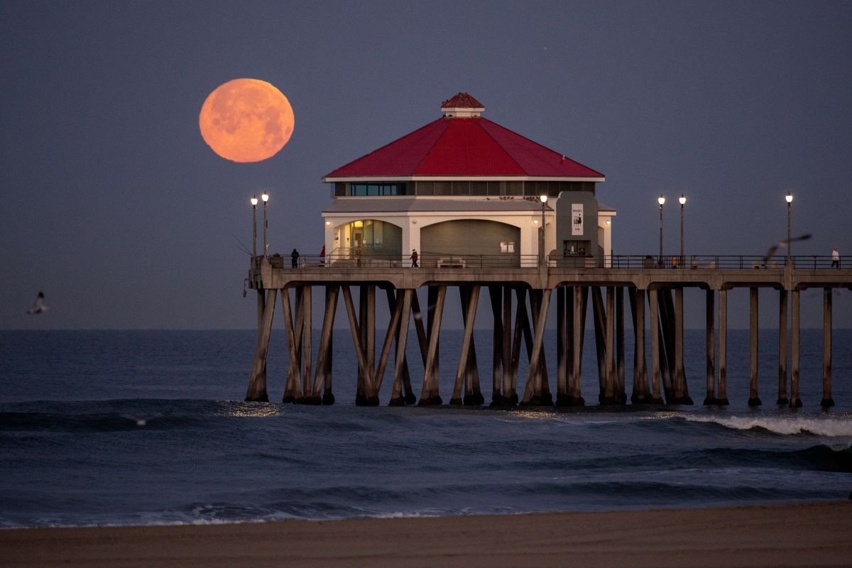 米カリフォルニア州ハンティントンビーチの桟橋の向こうに浮かぶ4月の満月「ピンクムーン」。2023年4月5日撮影（Allen J. Schaben / Los Angeles Times via Getty Images）