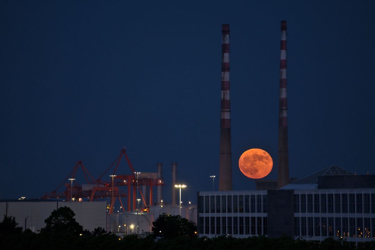 アイルランド・ダブリンのランドマークとして知られるプールベッグ発電所の2本の煙突の間から昇るスーパー・フラワームーン。2021年5月26日撮影（stock.adobe.com）