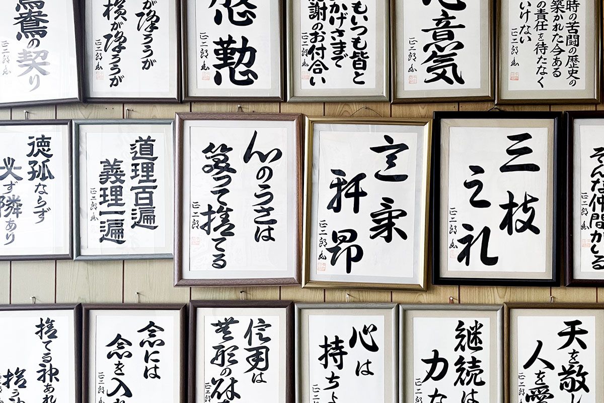 今富正二郎さんの仕事場の壁一面には、隙間なく書が掲げられていた。それぞれの額には、見えているものだけではなく、数枚の書が入っている。