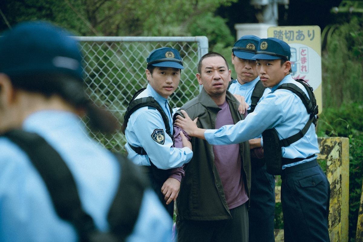 子どもの行方不明事件が囁かれるなか、不審者として大吾は警官に拘束されてしまう ©2026フジテレビジョン・ギャガ・東宝・AOI Pro.
