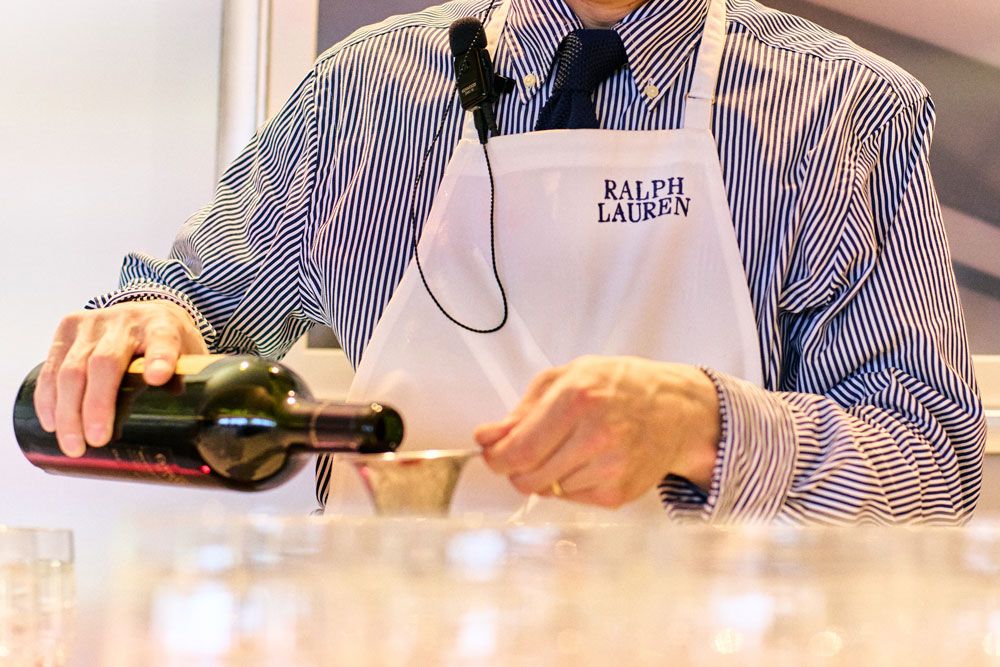 「RALPH LAUREN」のエプロンをまとい、グラスにドリンクを注ぐスタッフ。細部のもてなしまで、ブランドの手が行き届いていた。