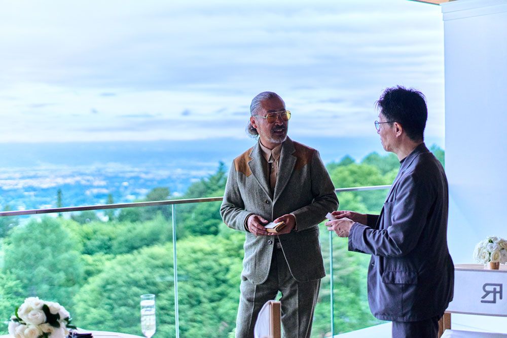 山々を背に、立ち話が続く。半分プライベートで半分仕事のような時間が、思いがけない出会いを連れてくる。